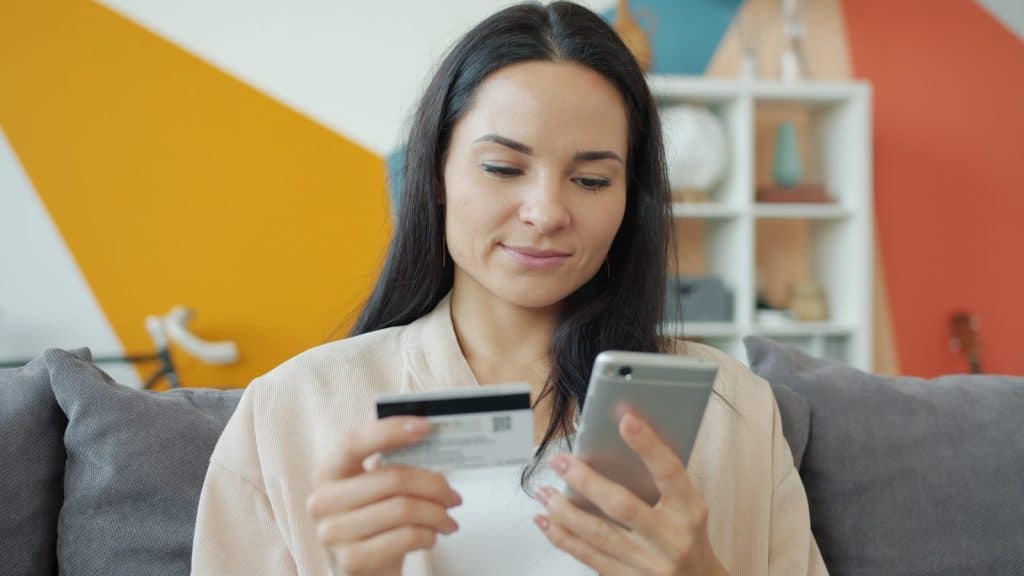 Customer entering credit card information on a smartphone — building trust on a Shopify storefront with embedded Etsy reviews